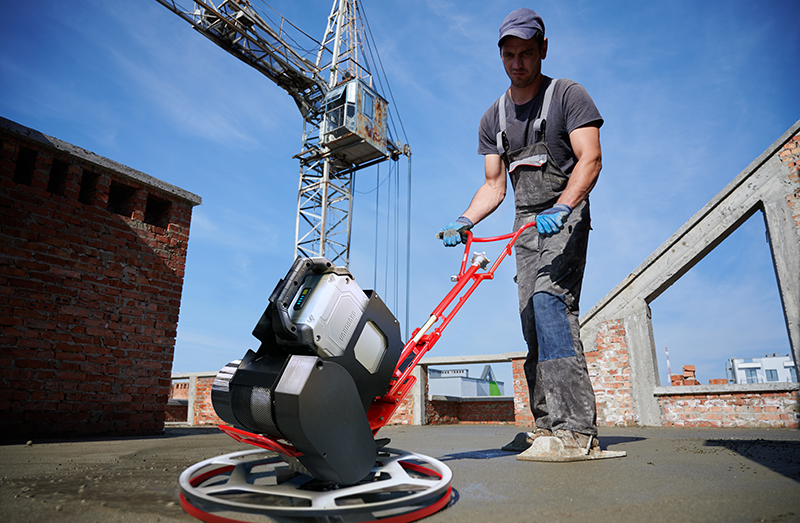 Man operating a concrete power trowel with the Vanguard swappable battery