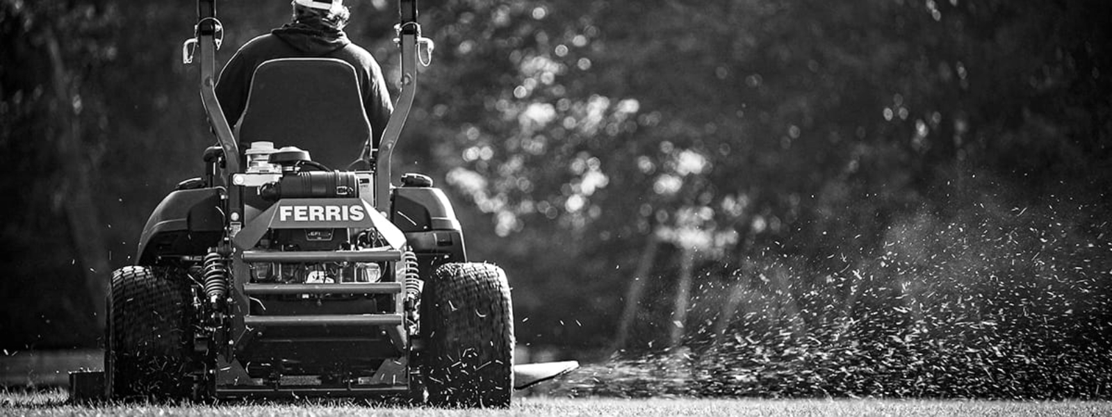 A person uses a Ferris® riding lawn mower to cut grass.