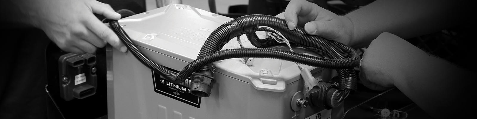The hands of two people working to connect a wire harness to a Vanguard 48-volt, 3.5 kilowatt-hour lithium-ion battery pack.