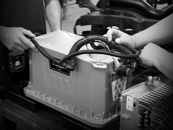 The hands of two people working to connect a wire harness to a Vanguard 48-volt, 3.5 kilowatt-hour lithium-ion battery pack.