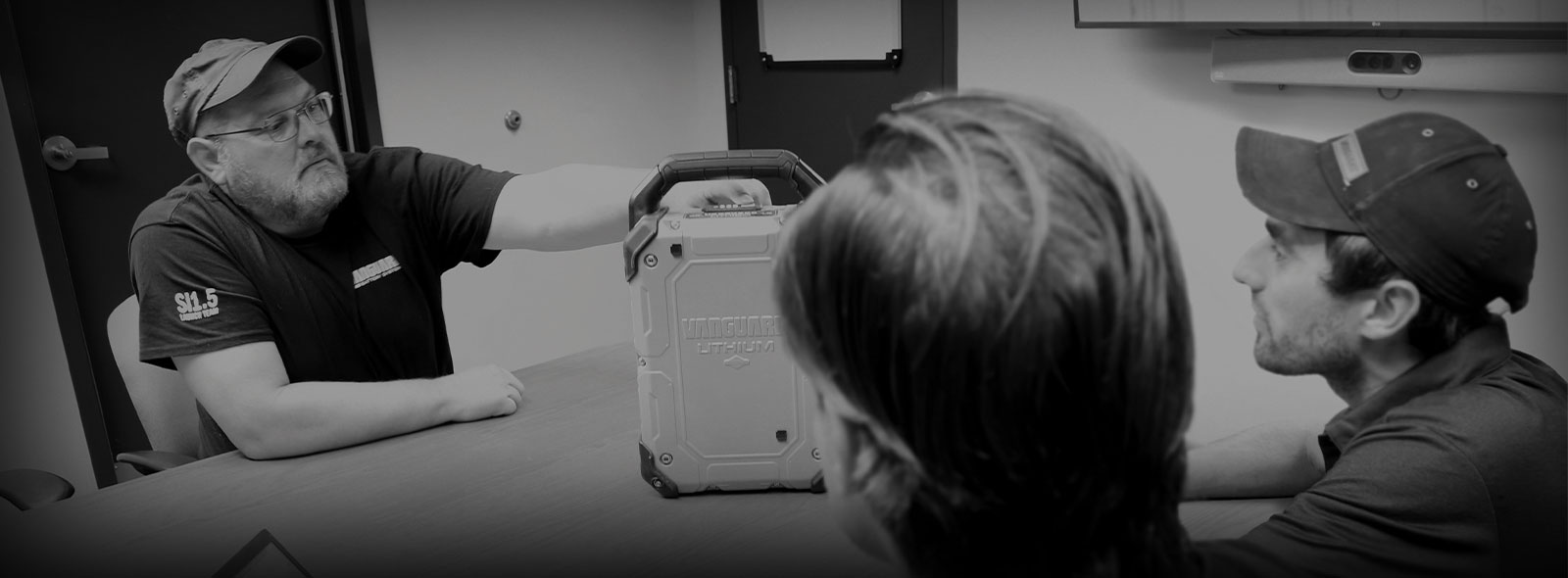 Three Vanguard engineers examine a Vanguard lithium-ion battery pack. 