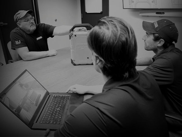Three Vanguard engineers examine a Vanguard lithium-ion battery pack. 