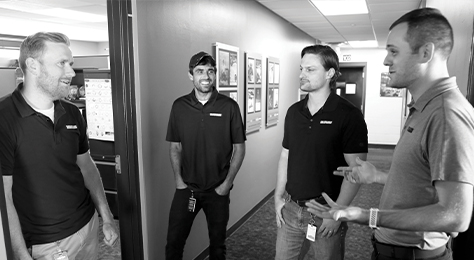 Three Vanguard engineers and a Vanguard Battery Technology Partner talk in a hallway.